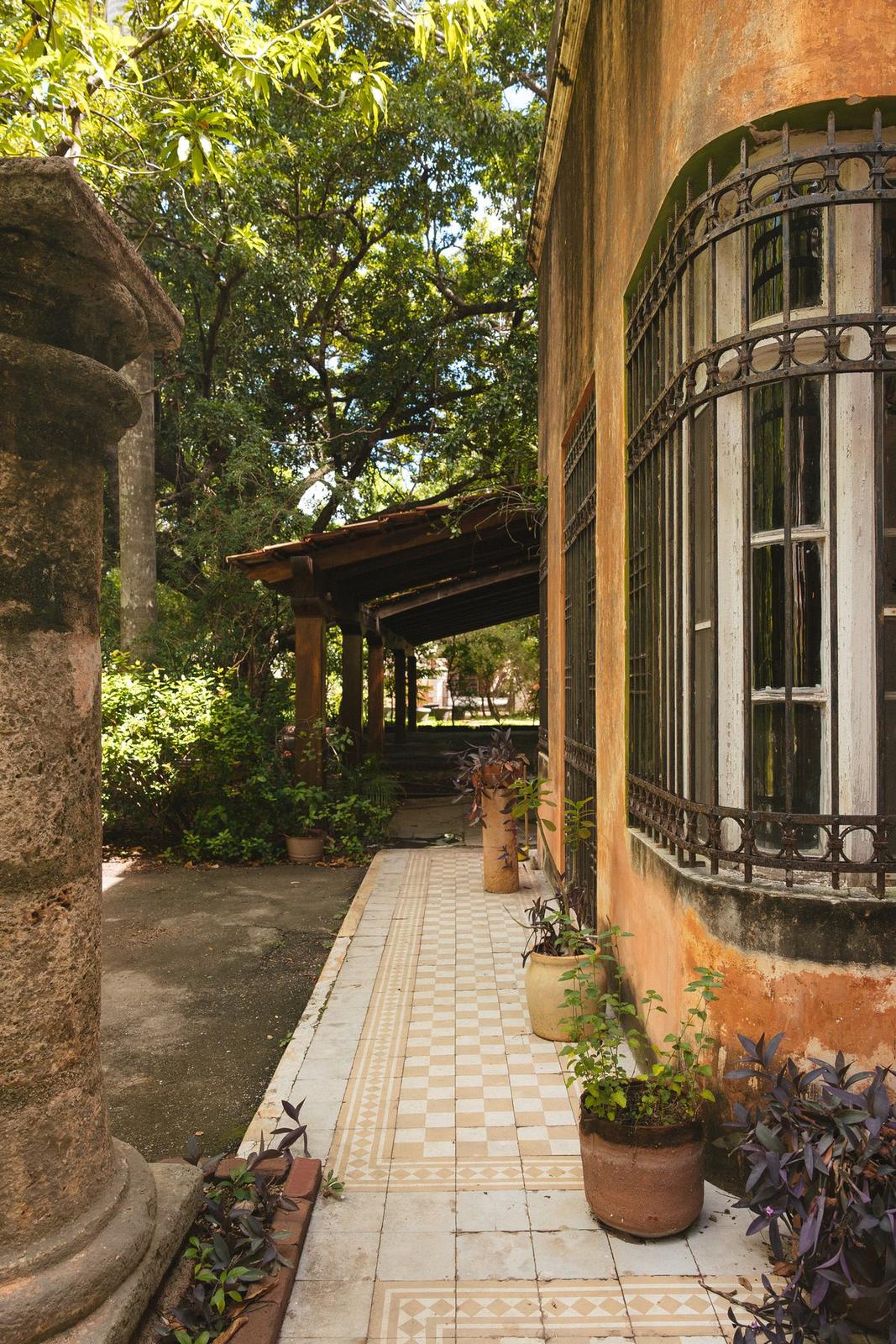 Terraza con reja, columnas y macetas hacia el jardín
