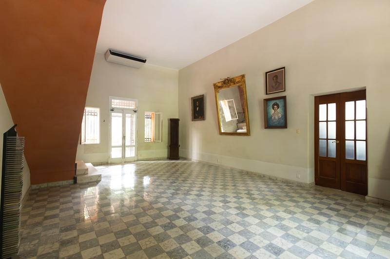 Salón principal con piso de pasta gris, espejos y la escalera
